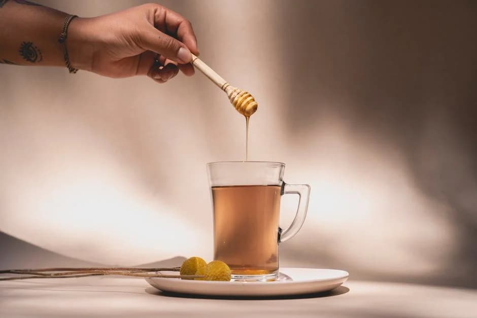 Warm honey water in a clear mug with a wooden honey dipper