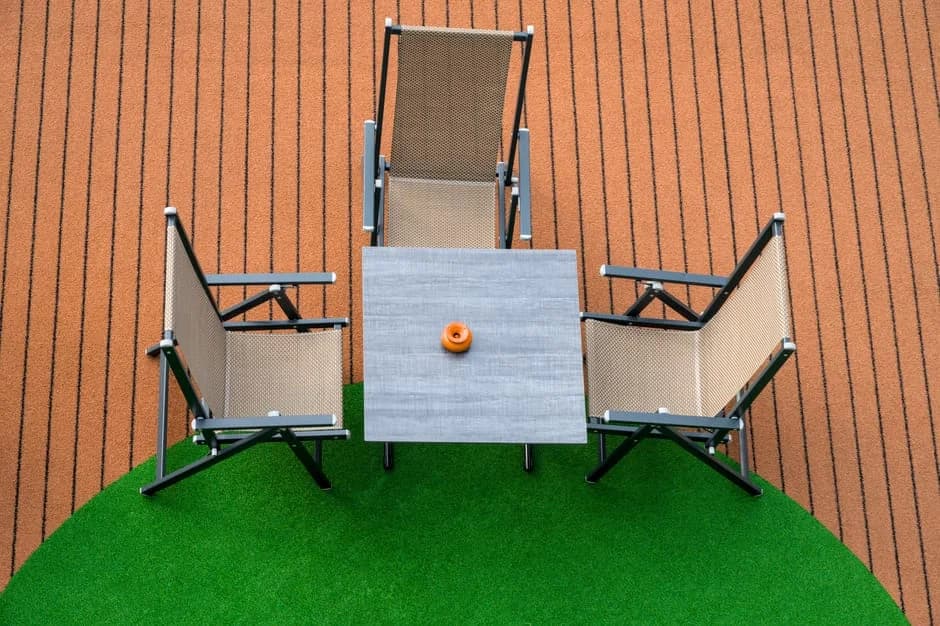 Top view of a modern patio furniture set with three chairs and a table on artificial grass.