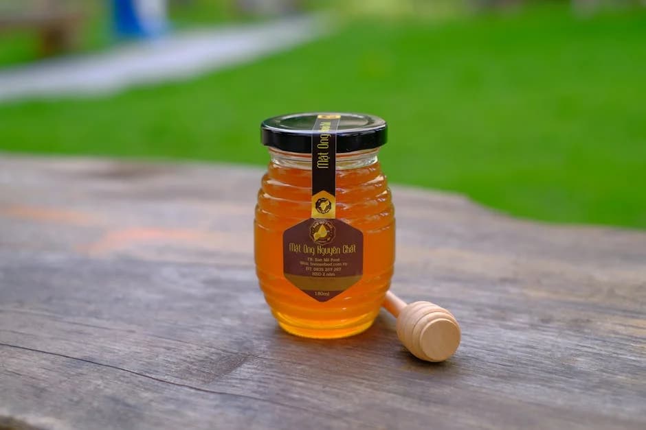 Jar of raw Canaan honey with a wooden dipper, showing its golden amber color and thick texture